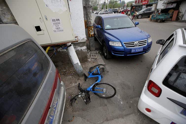 In the outskirts of Beijing, this shared bike lies abandoned among vehicles.
