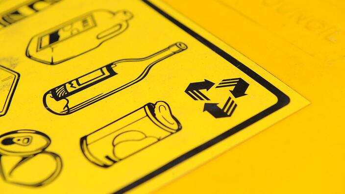 A sticker illustrating what products can be placed in a recycling bin.