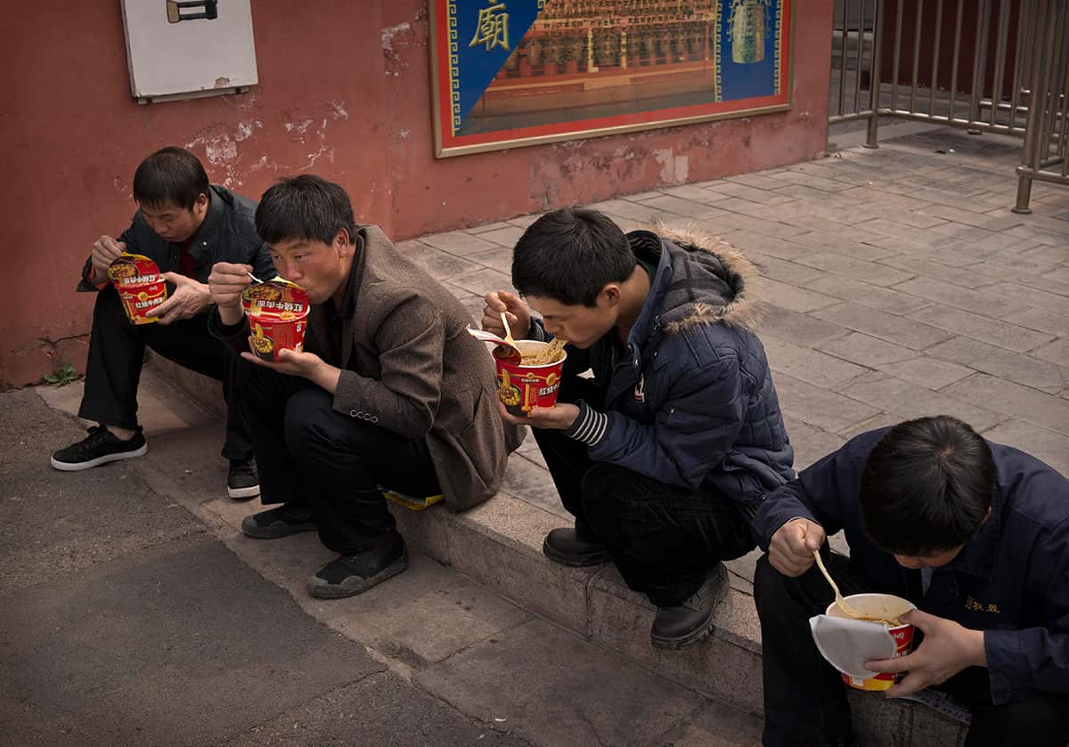 Chinese men eat noodles