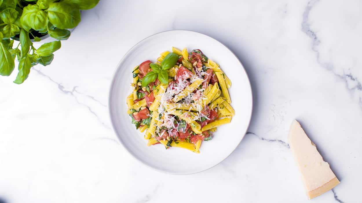 Chopping board tomato and basil pesto pasta