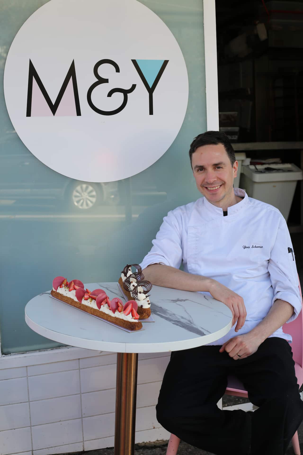 Owner of Clovelly's Madame and Yves, Yves Scherrer, with two of his eclairzilla creations: (L) strawberries and cream, and (R) chocolate and cream.