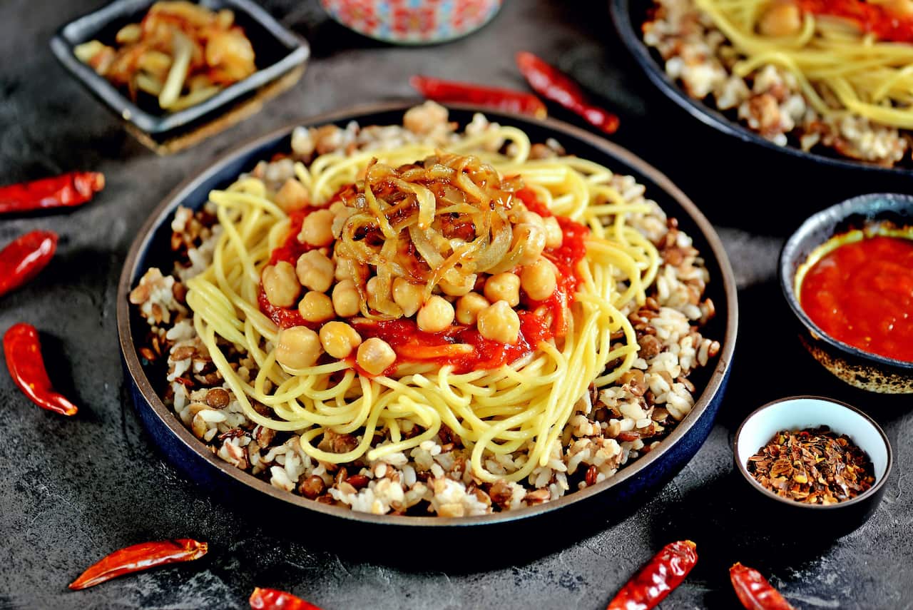 Kushari or Koushari - Egyptian dish of lentils, rice, pasta, chickpeas with tomato sauce and crispy onions. Arabic cuisine