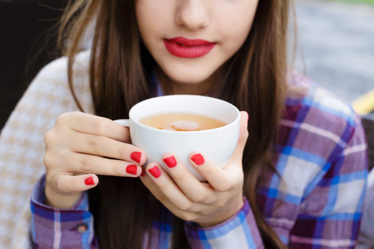 Girl wrapped in a blanket drinking a tea  in outdoor cafe