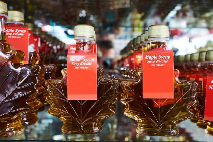 Rows of maple leaf shaped bottles containing maple syrup on shop shelf, Canada
