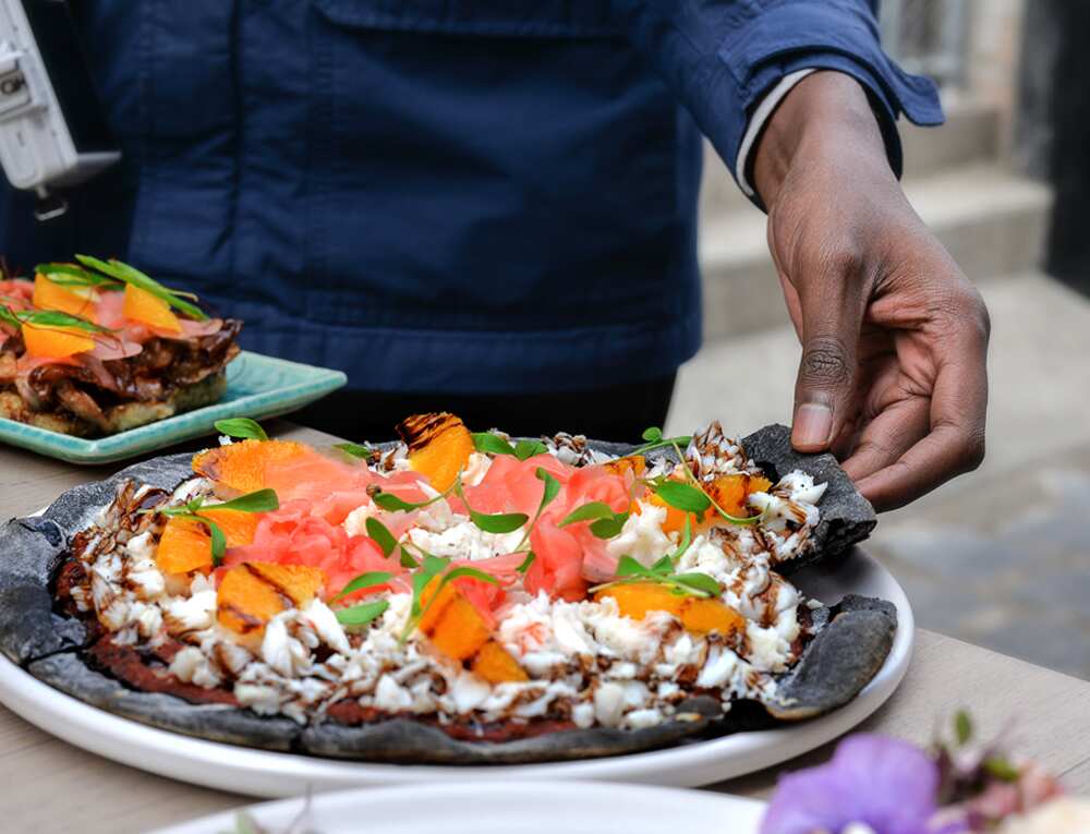 The sashizza sees raw fish piled onto squid ink pizza bases.