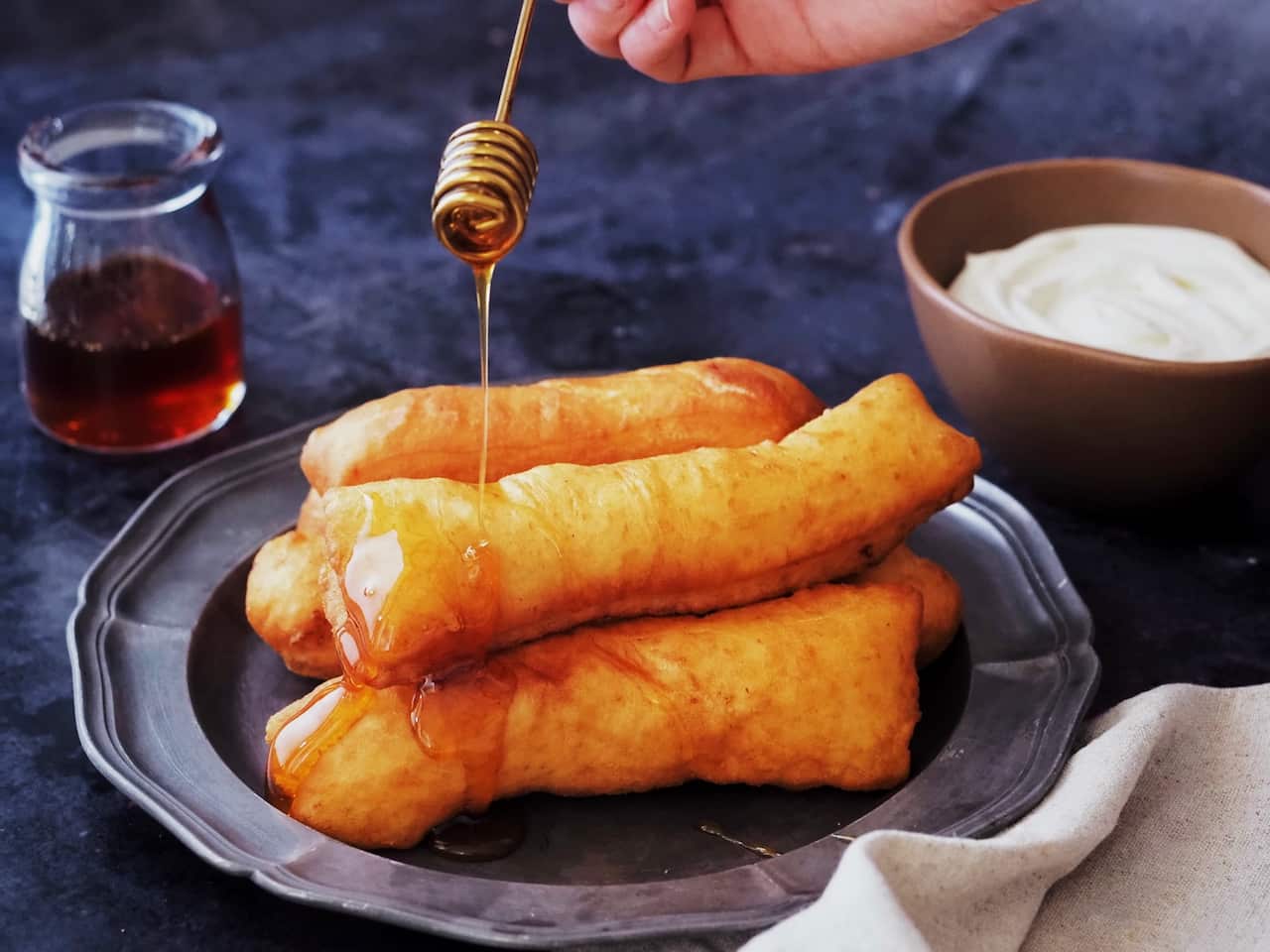 Bosnian fried pastry being drizzled with honey