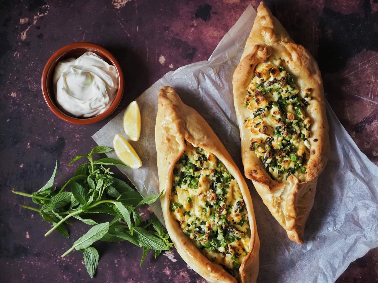Pea, mint, and haloumi pide, served with wedges of lemon, yoghurt and fresh mint
