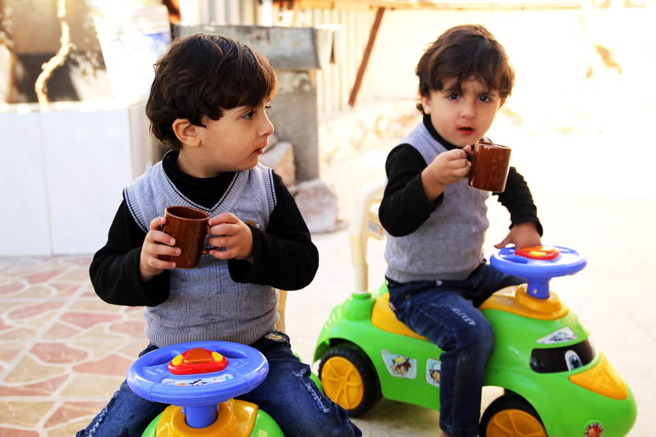Shaldan's twin grandsons share a drink in the courtyard.