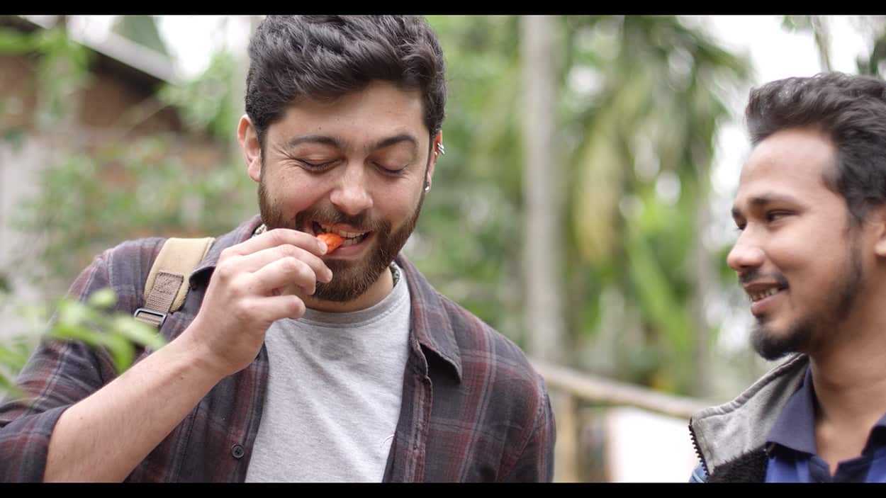 Pablo Naranjo Agular tries a chilli during a visit to the cillage of Jorhat in Assam