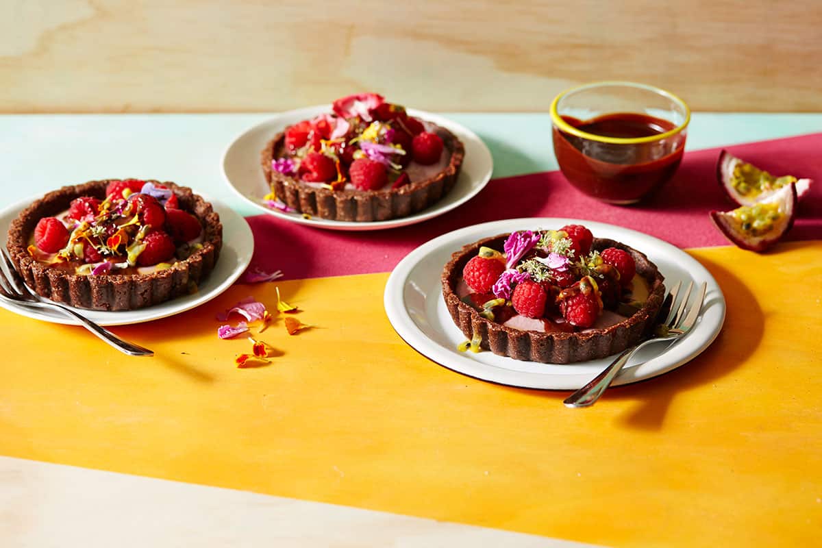 Raw raspberry, ginger and chocolate tarts with passionfruit and dark chocolate sauce