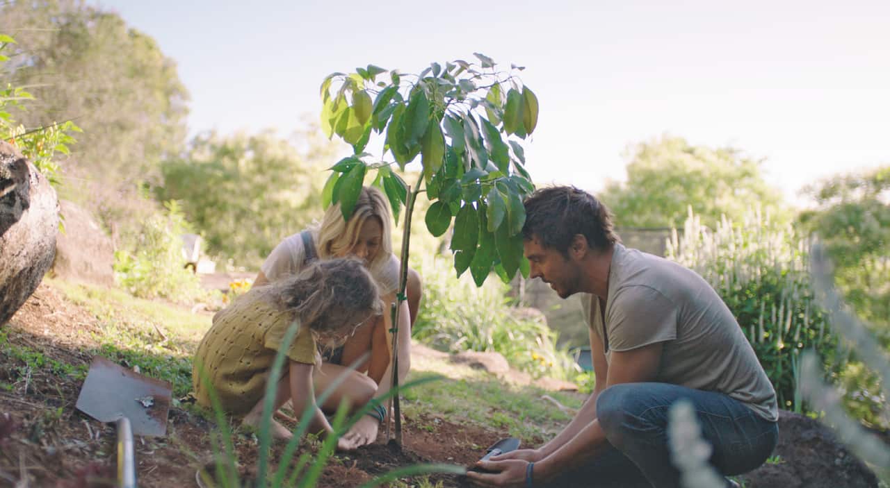 Daman Gameau, his wife and daughter plant a tree together.