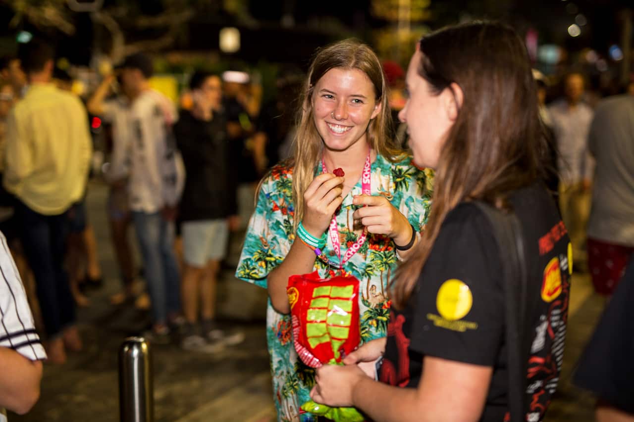 Schoolies attendees accepting red frogs from volunteers.