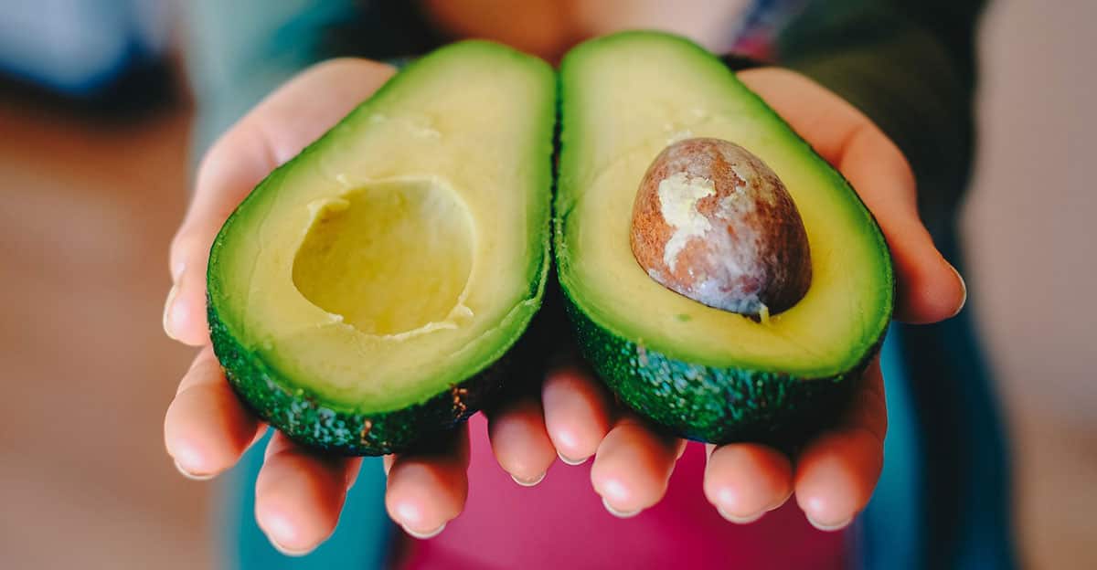 Woman holding cut avocado