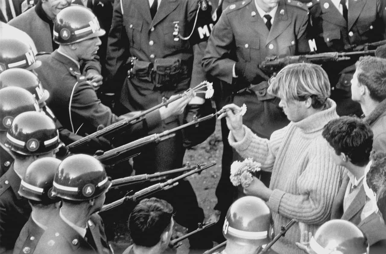 An antiwar demonstrator places flowers into the barrels of rifles while blocking the Pentagon on Oct. 21, 1967.