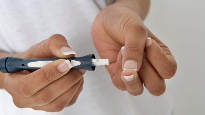 Woman injecting insulin using syringe close-up of hands