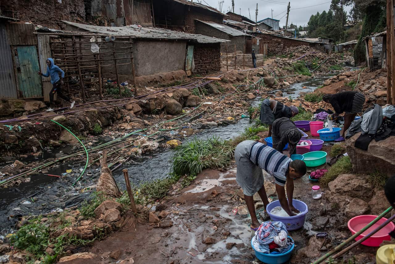 Washing clothes in a stream polluted with sewage. Human waste is unavoidable in Kibera.