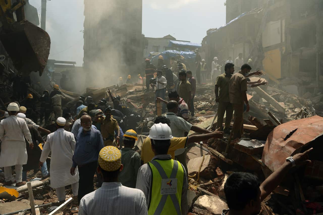 Rescue workers and residents look for survivors at the site of a building collapse in Mumbai on August 31, 2017. At least three people died and dozens were feared trapped when a building collapsed in Mumbai, after days of heavy rain swamped the city.