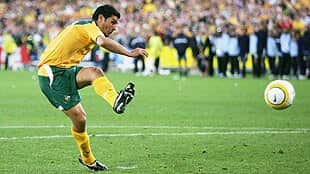 John Aloisi playing for Australia and kicking the ball 