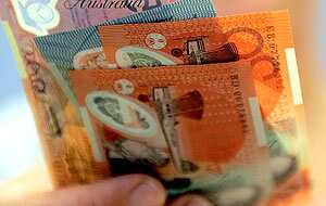 A hand holding Australian banknotes