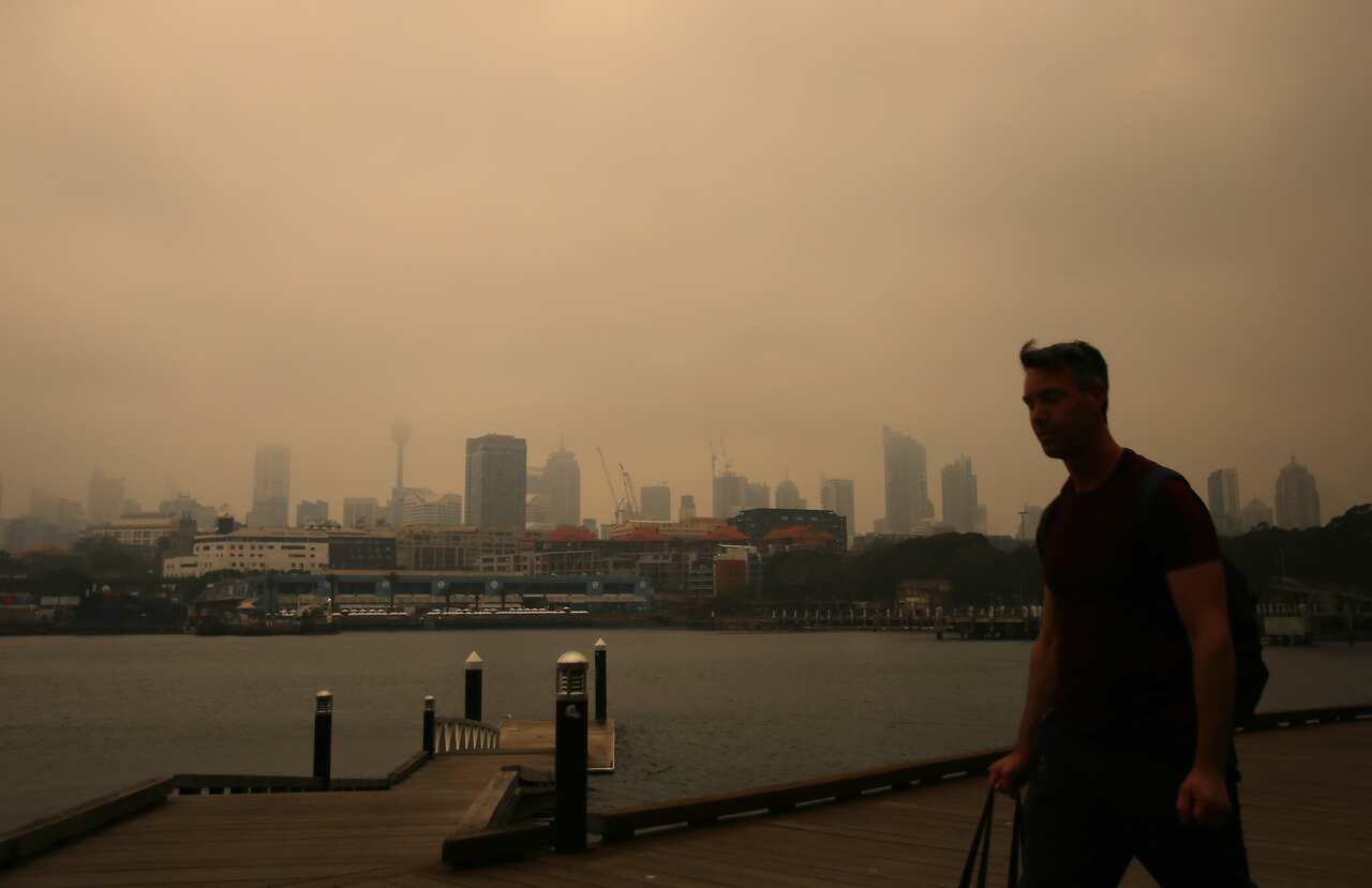 A man walks long the foreshore in Blackwattle bay as smoke haze from bushfires in New South Wales blankets the CBD in Sydney last week. 