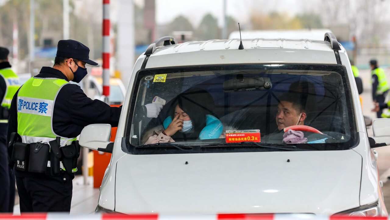 A militia member checks the body temperature of a passenger on a vehicle at an expressway toll gate in Wuhan, central China's Hubei province.