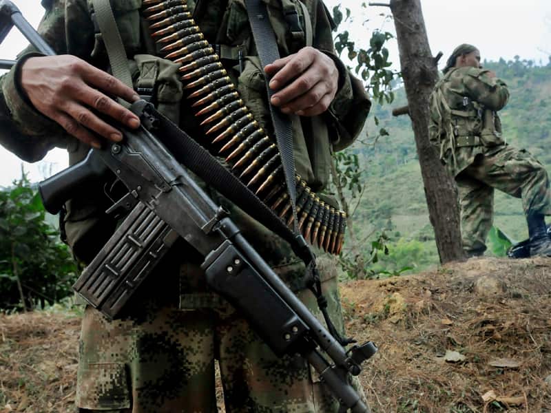 A man carries an automatic weapon in the jungle