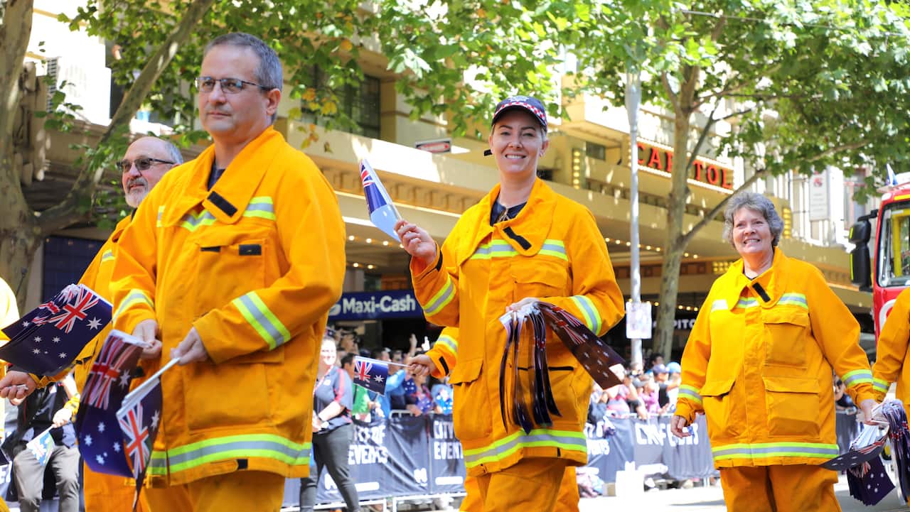 Firefighters carry Australian flags as they are honoured at the march in Melbourne.