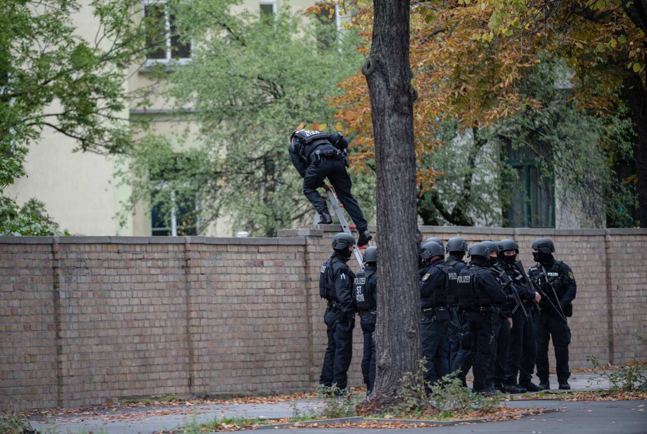 Police entry a Jewish cemetery over a wall near the scene of a shooting