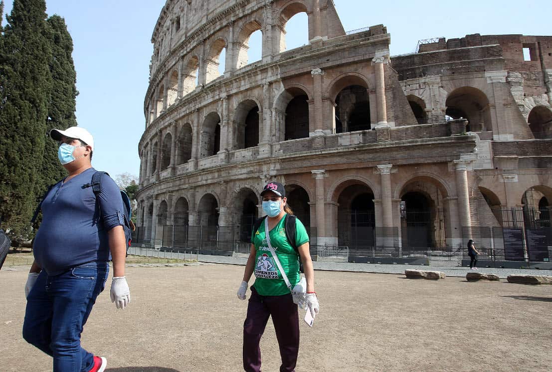 People wearing face masks outside the Colosseum in Rome.