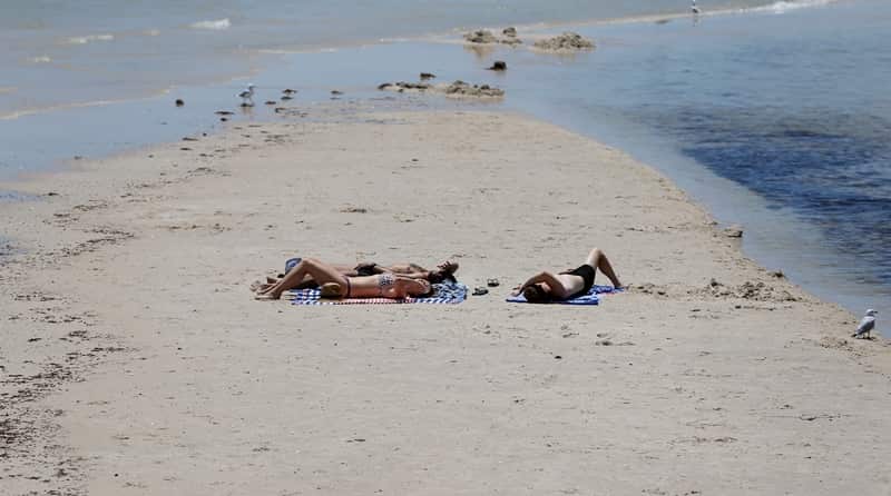 Beach goers sunbath on the sands of Henley Beach during a hot day in Adelaide, Thursday, January 3, 2019. Temperatures soared across South Australia today, climbing close to 50C in some regional towns. (AAP Image/Kelly Barnes) NO ARCHIVING