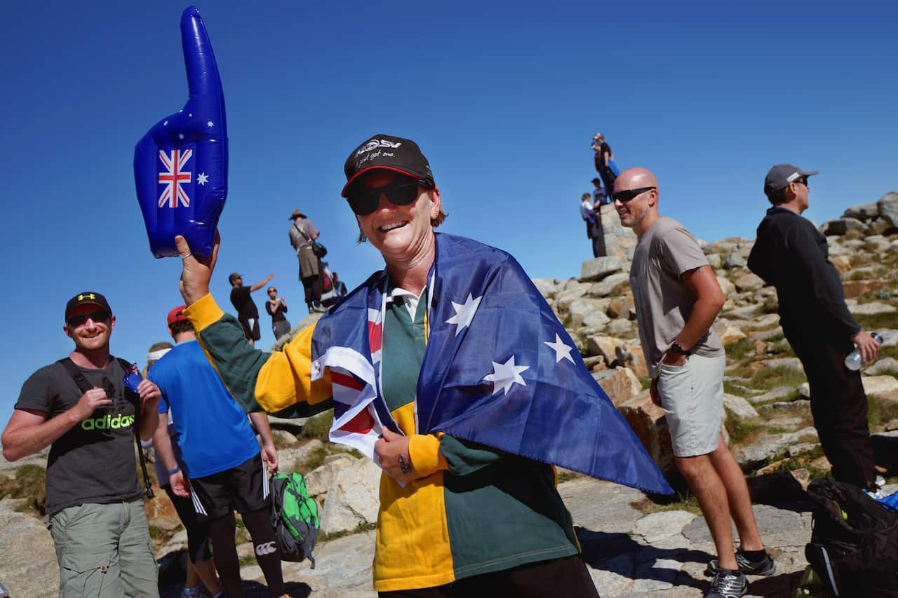 A woman draped in an Australian flag and holding a blue inflatable hand wth an Australian flag on it