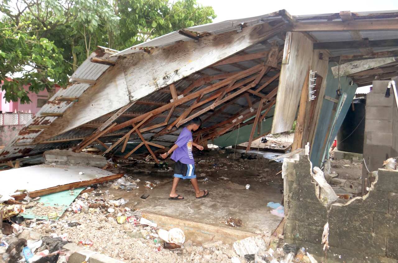 A boy walks under a damaged house at Majuro Atoll in the Marshall Islands (AAP)