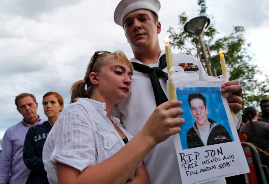 US Navy Officer Keith Hoover with his girlfriend Monica Matryba hold a photo of fellow sailor Jon Larimer, who was killed during the Aurora shooting.