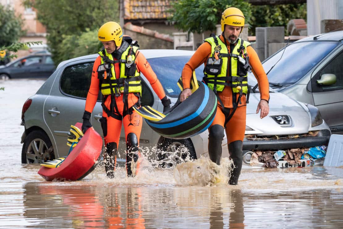 Rescue workers wade through muddy waters searching for survivors in the town of Trebes.