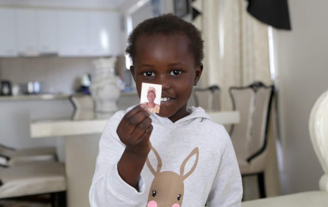 Mary’s daughter Nyankor Dhor, aged 3 years holds a picture of her grandmother who she has never met.