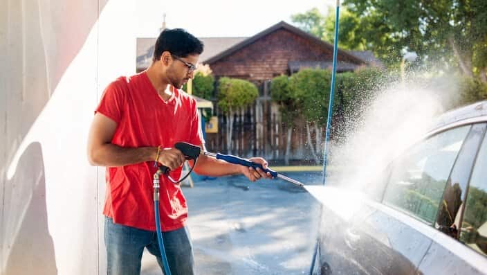 Man washing car in garage on sunny day