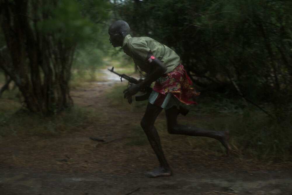 Believing they are under attack, a boy with an AK-47 races to the scene where a potential fight has broken out. (Matthew Abbott) (Matthew Abbott)