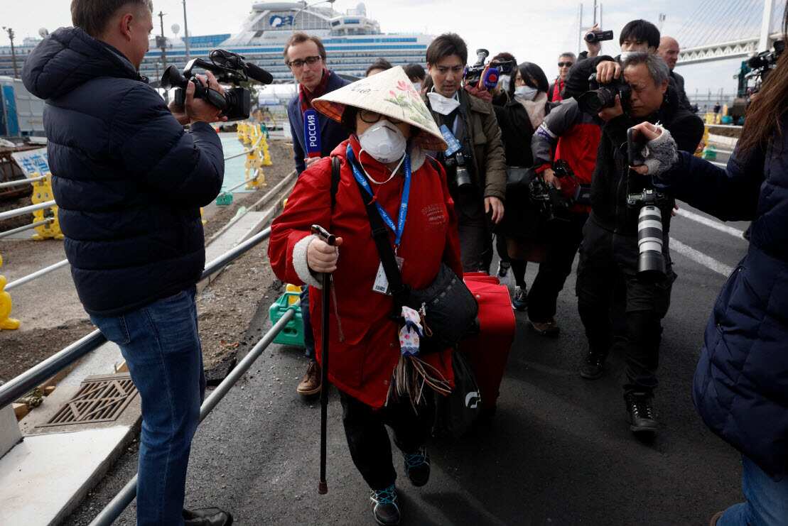 An unidentified passenger is surrounded by the media after she disembarked from the quarantined Diamond Princess cruise ship Wednesday, 19 February, 2020.