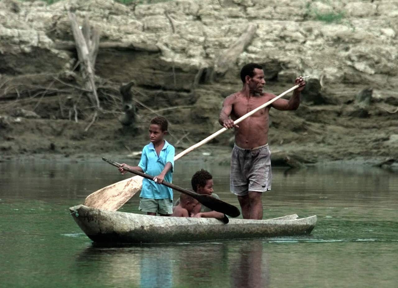 A family paddle a wooden canoe across the Fly River near the town of Kiunga in the Western Province of Papua New Guinea.