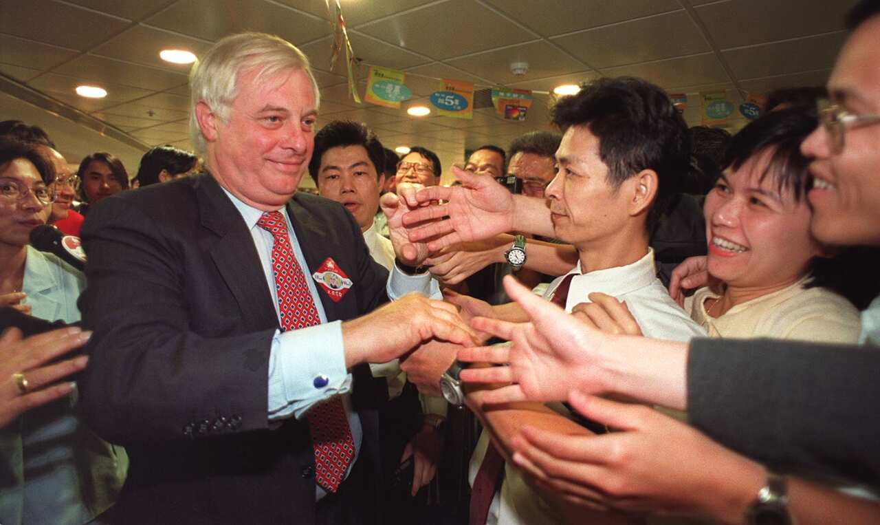 The last British Governor of Hong Kong Chris Patten, left, is greeted by well-wishers at a shopping center in 1998.