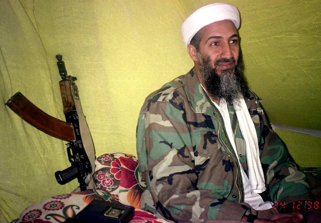 An AK47 assault rifle at his side, Osama Bin Laden speaks to a selected group of reporters in southern Afghanistan. (1998)