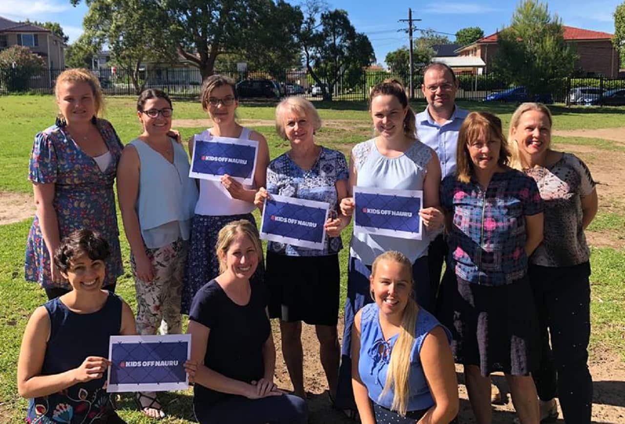 Teachers hold #KidsOffNauru placards.
