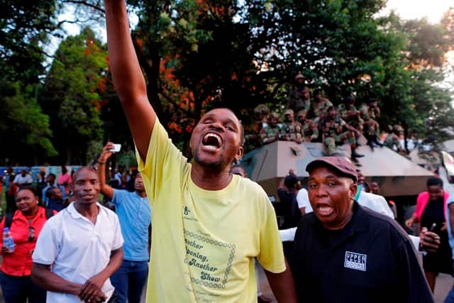 People celebrate outside parliament after hearing the news that President Robert Mugabe resigned in Harare, Zimbabwe, 21 November 2017. 