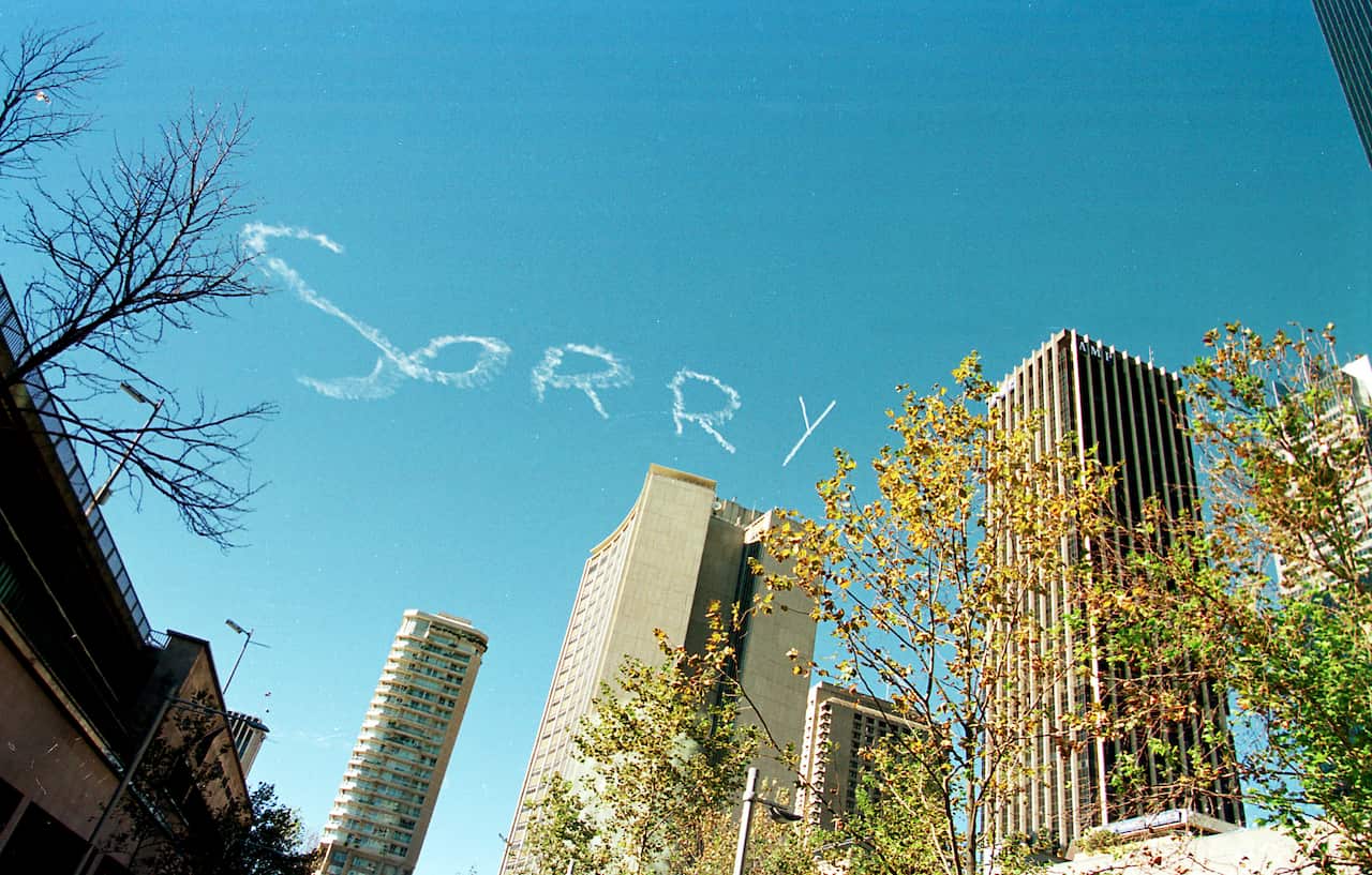 Crowds of people crossing the bridge cheered when a plane wrote "Sorry" over the Sydney skyline.