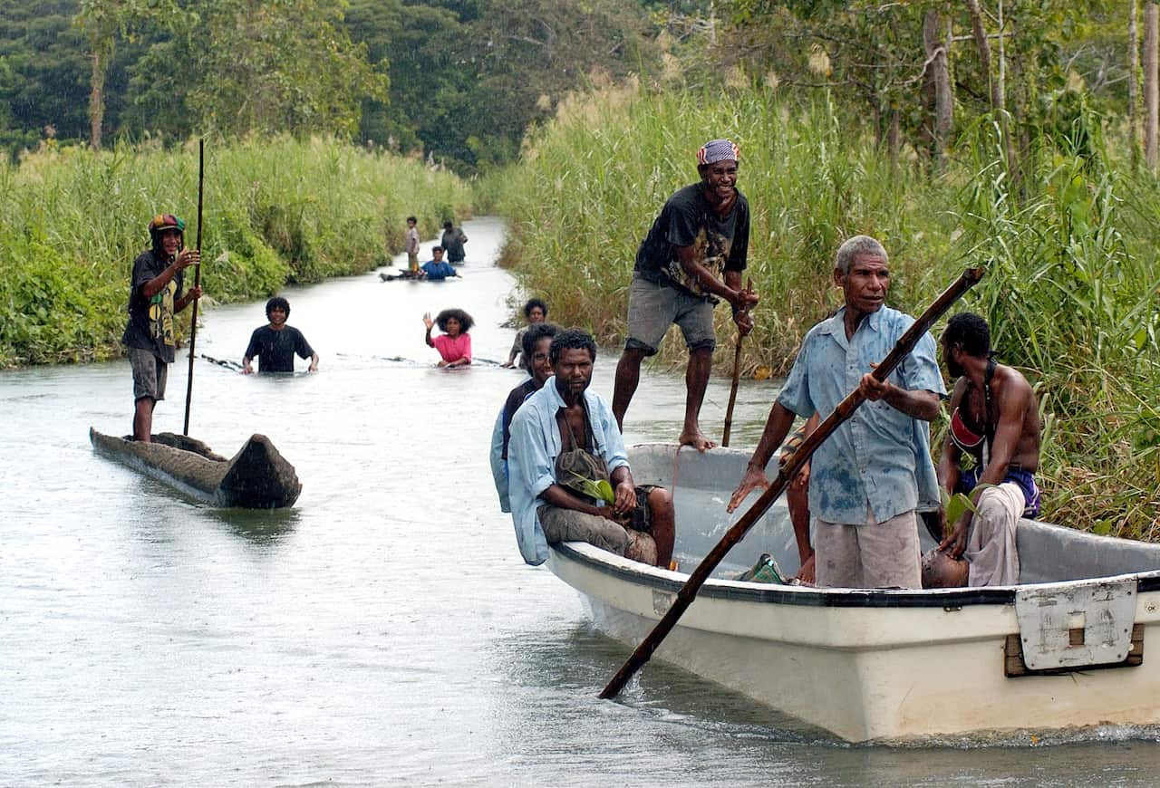People from flooded Biotou village in Papua New Guinea's Central Province wade or pole their way in dug-out canoe.