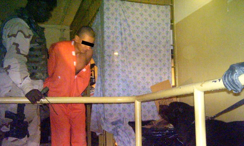 A photo released by SBS' Dateline on 15 February, 2006 allegedly shows a prisoner (C) in Iraq's Abu Ghraib prison being held by a US soldier (L) in front of a dog (R) in Baghdad in 2004.