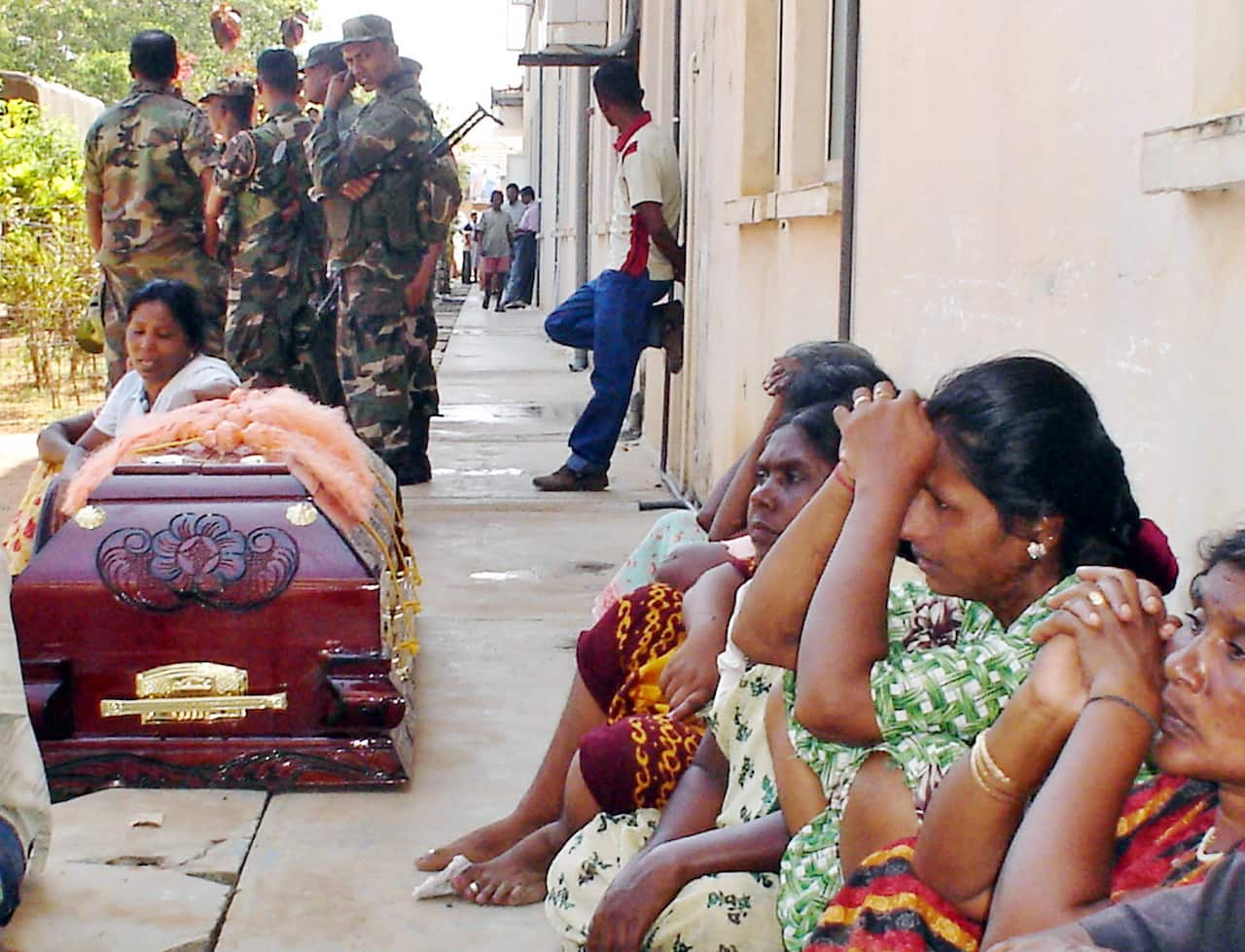 Women wait near coffins to receive the bodies of relatives who died in an explosion in a vegetable market in Trincomalee, Sri Lanka, Thursday, April 13, 2006. 