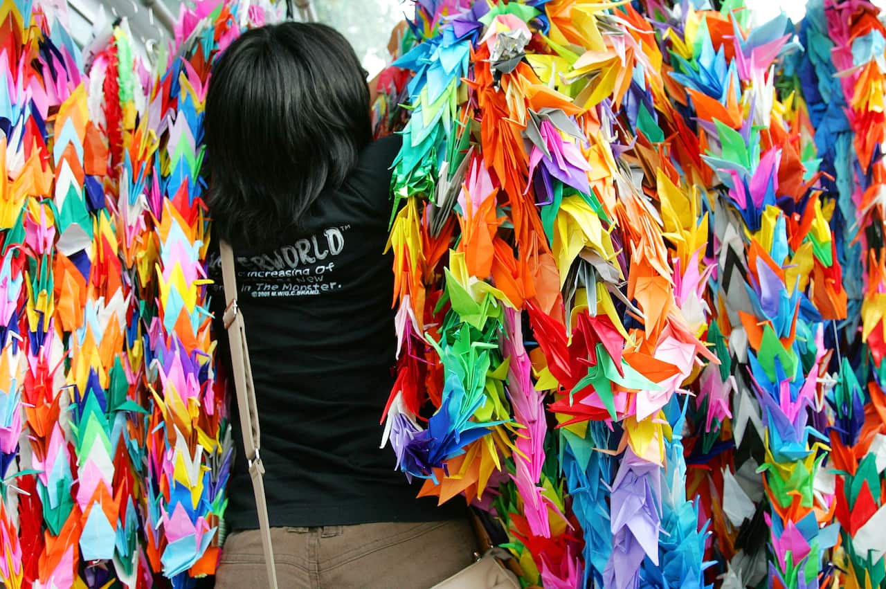 A tourist hangs a bundle of paper cranes to add on to thousands of them at Hiroshima Memorial Peace Park. (AP Photo/Shizuo Kambayashi)