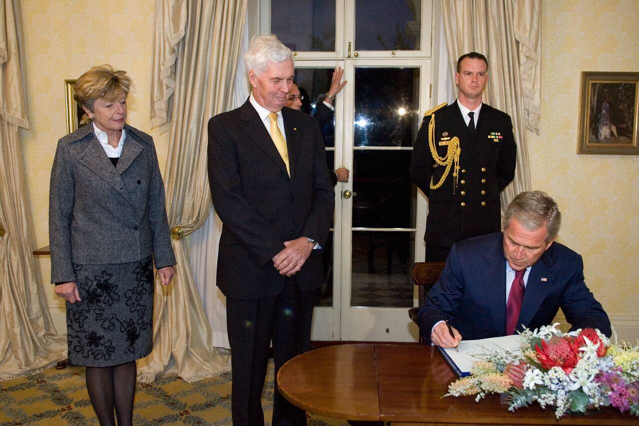 US President George W Bush signs the visitor book with Governor General Michael Jeffery (centre) and his wife Marlena at Admiralty House in Sydney in 2007. 
