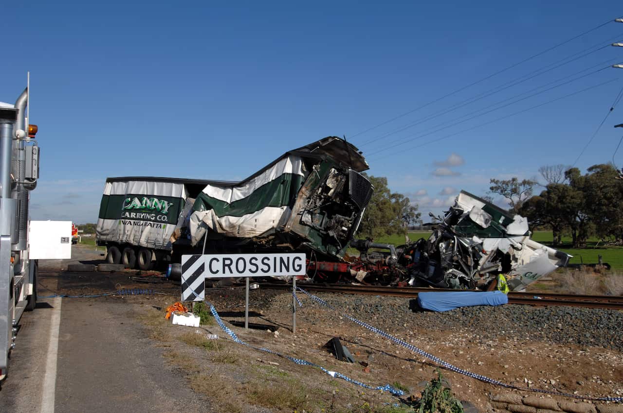 Emergency service workers inspect the truck at the point where it hit a V-Line train at a level crossing near Kerang, northern Victoria.